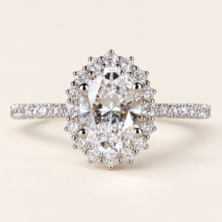 Oval cut lab grown diamond halo engagement ring in white gold with scalloped round diamond halo, pavé shoulders and raised center prongs.