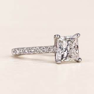 Princess cut lab grown diamond engagement ring in white gold with four-prong center and round pavé-set shoulders