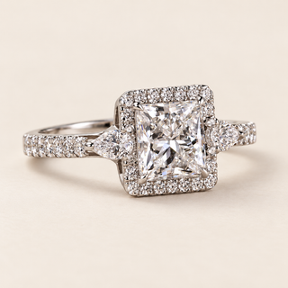 Princess cut lab grown diamond halo engagement ring with 0.80 ct center, square pavé halo, pear-shaped side diamonds and pavé shoulders in polished white gold.