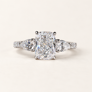 Elongated cushion cut lab grown diamond three stone engagement ring in white gold with pear side diamonds and pavé shoulders