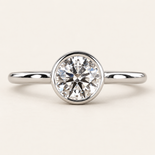 Round lab grown diamond bezel engagement ring in white gold with a continuous polished rim and plain band