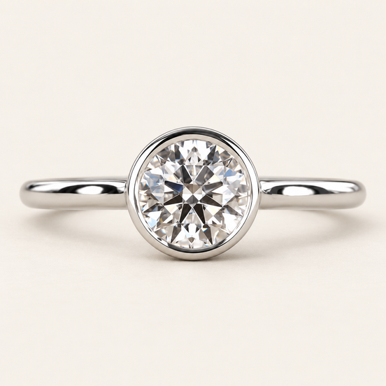 Round lab grown diamond bezel engagement ring in white gold with a continuous polished rim and plain band