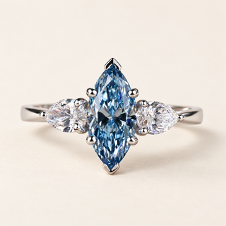 Blue marquise lab grown diamond three-stone engagement ring in white gold with V-shaped tip guards and outward-pointing pear side diamonds