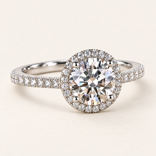 Round lab grown diamond halo engagement ring in white gold with four-prong center, pavé halo and diamond-set shoulders