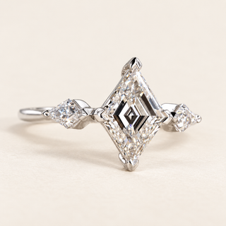 Lozenge step cut Lab Grown Diamond three stone engagement ring in white gold with matching lozenge side diamonds and double-claw prongs.