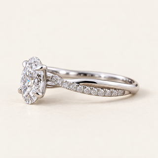 Oval cut lab grown diamond crossover engagement ring in white gold with four-prong center, twisted pavé shoulders and polished band