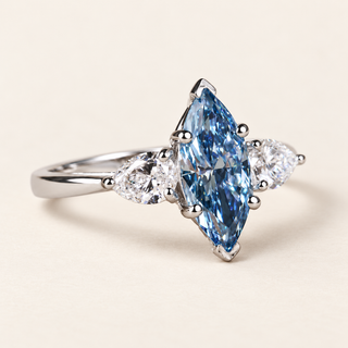 Blue marquise lab grown diamond three-stone engagement ring in white gold with V-shaped tip guards and outward-pointing pear side diamonds