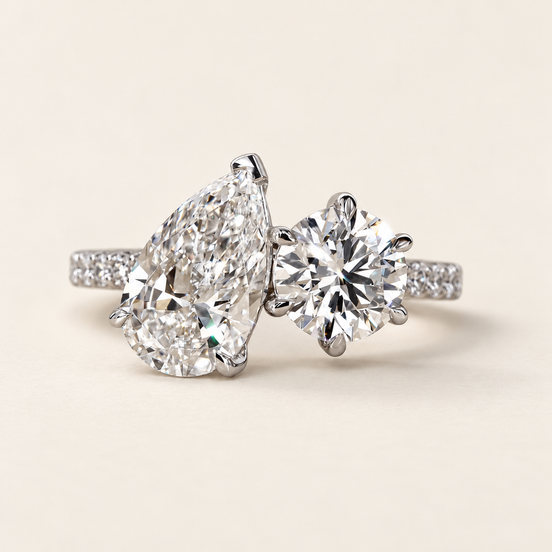 Pear cut lab grown diamond two-stone engagement ring with 2.00 ct pear, 1.25 ct round diamond, raised open baskets and pavé shoulders in white gold.