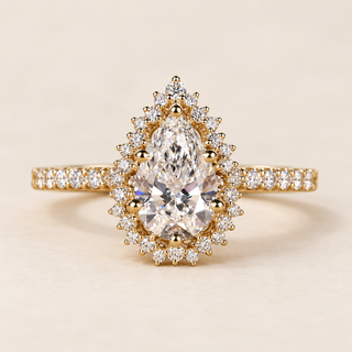 Pear cut lab grown diamond halo engagement ring with 1.00 ct center, scalloped round diamond halo and pavé shoulders in polished yellow gold.