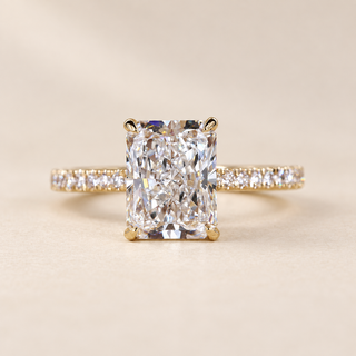 Radiant cut lab grown diamond engagement ring with 3 ct center stone, four-prong basket and pavé diamond band in yellow gold, front view.