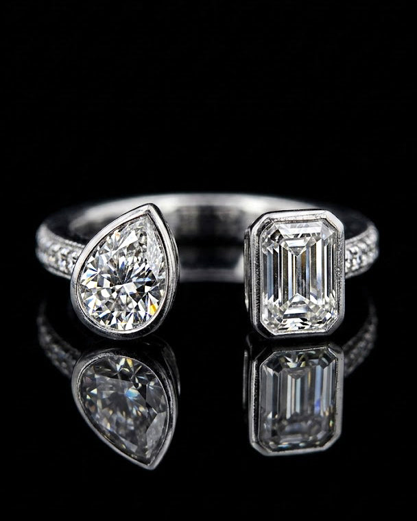 Main: White gold pear and emerald toi et moi ring with lab grown diamonds and pave shoulders on black
Detail: Close-up of pear and emerald-cut lab grown diamonds facing across an asymmetric white gold setting
Side: White gold two-stone ring with raised pear and emerald settings and round lab grown diamond accents