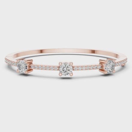 Elegant three stone round diamond bangle bracelet in gold with pavé accent diamonds by Signora Jewels