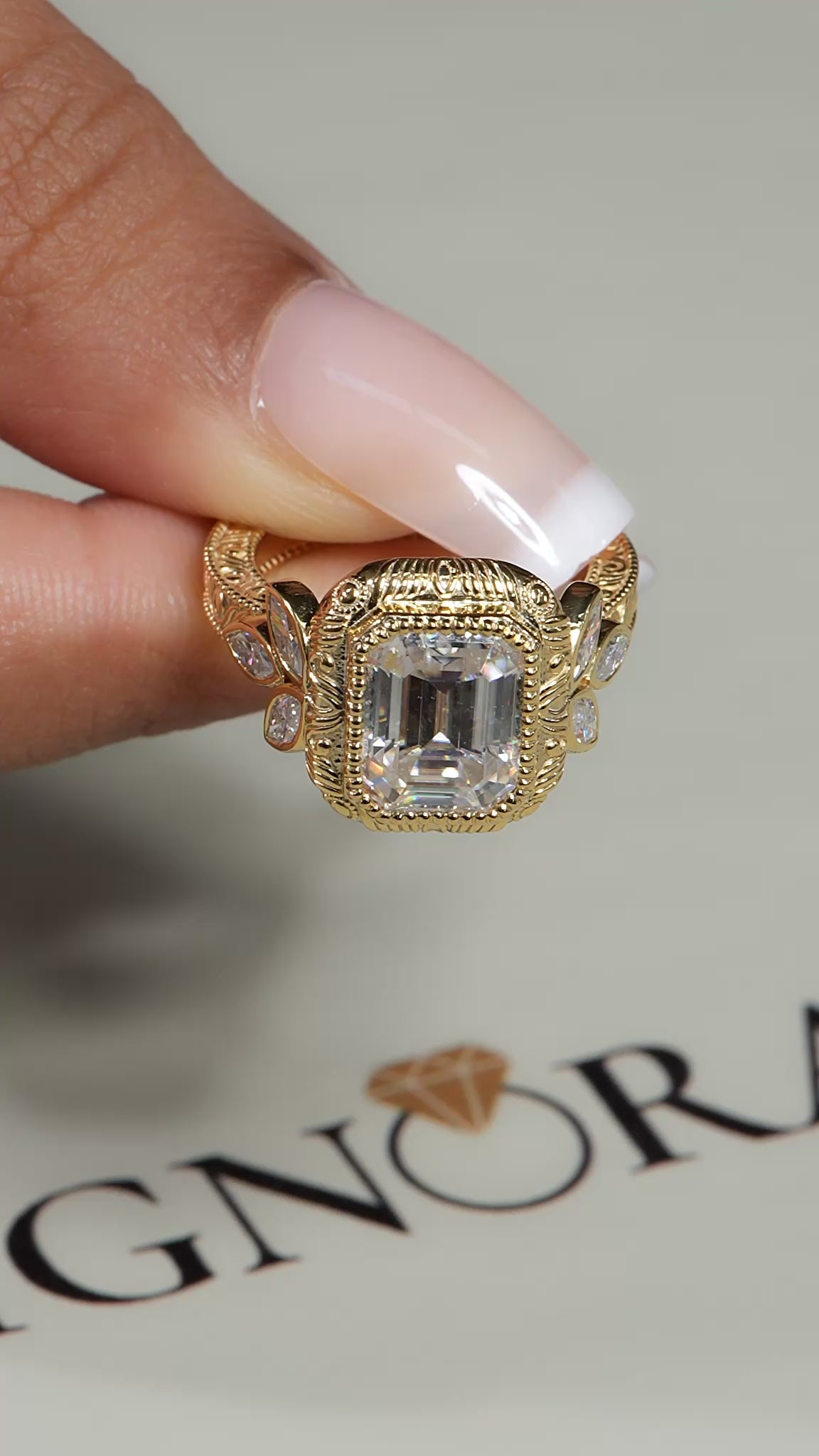 Emerald cut lab grown diamond vintage engagement ring in yellow gold with bezel center, marquise side diamonds and engraved shoulders