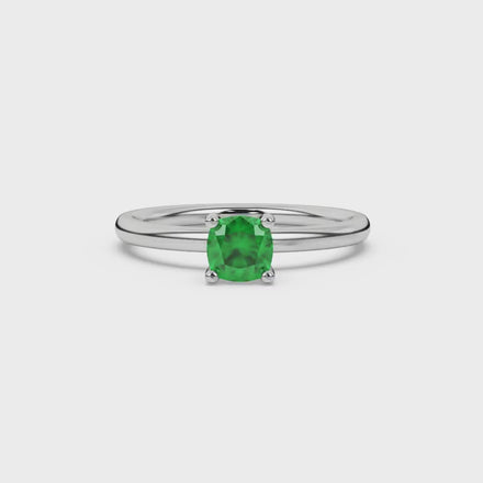 Green cushion cut gemstone solitaire ring in gold featuring a refined four-prong cathedral basket setting