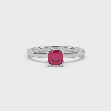 Red cushion cut solitaire gemstone ring in six-prong gold setting with slim stackable band